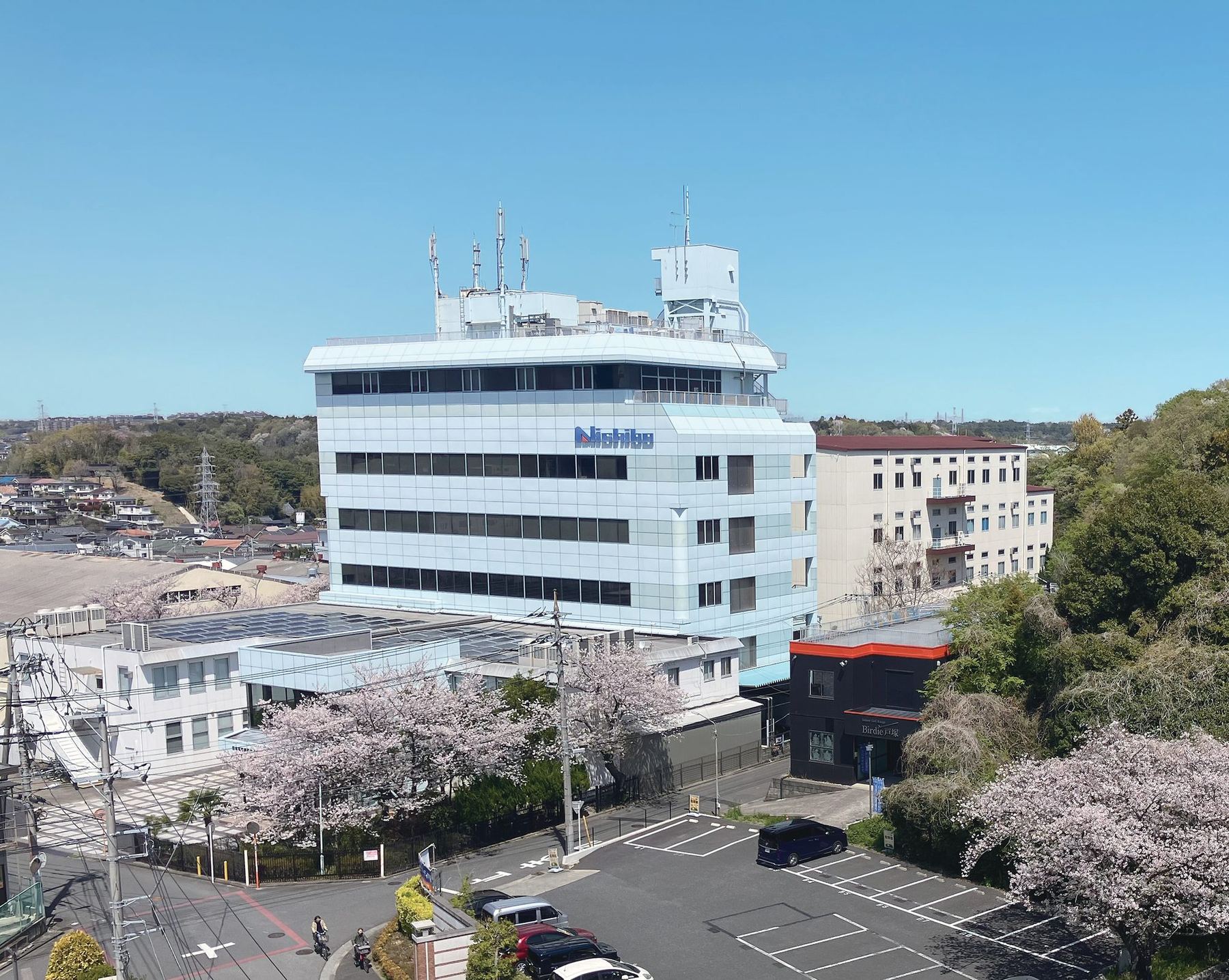 日本貿易印刷の本社。6階建ての白い社屋と、隣に並ぶ工場の建物